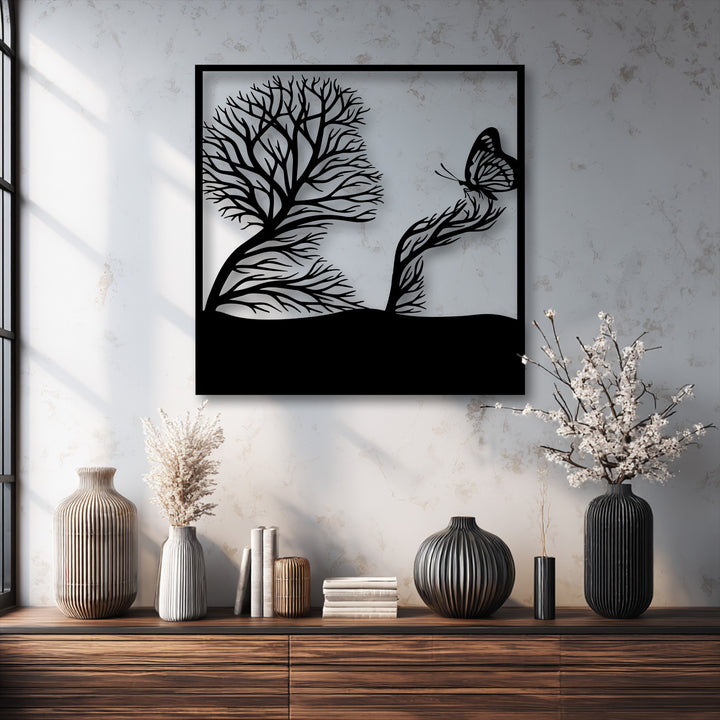The striking black silhouette of whimsical tree and butterfly artistic nature metal wall decor hangs prominently over a rustic wooden dresser.