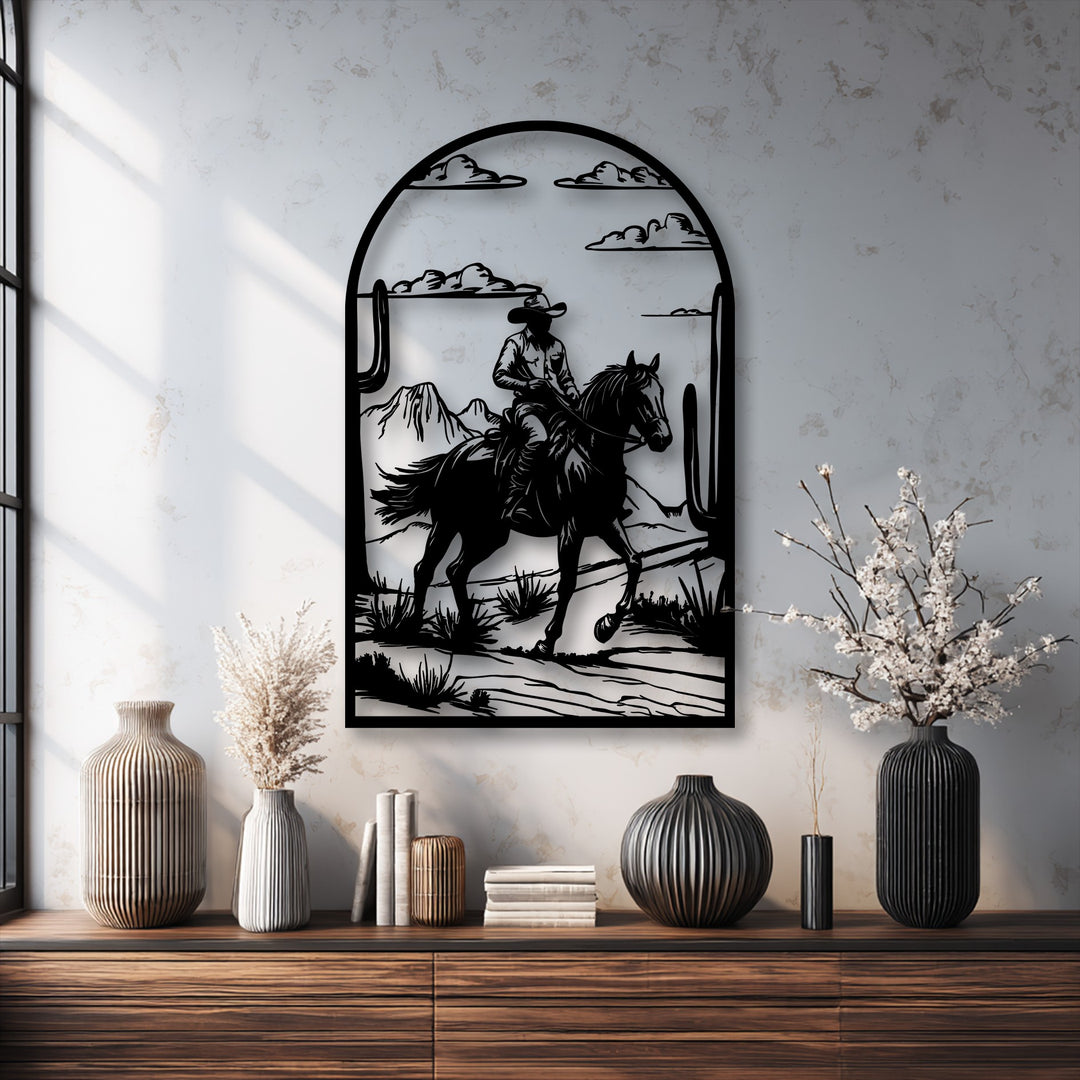 Against a creamy white wall, this striking metal wall decor showcases a western desert cowboy ride with mountains and cacti.