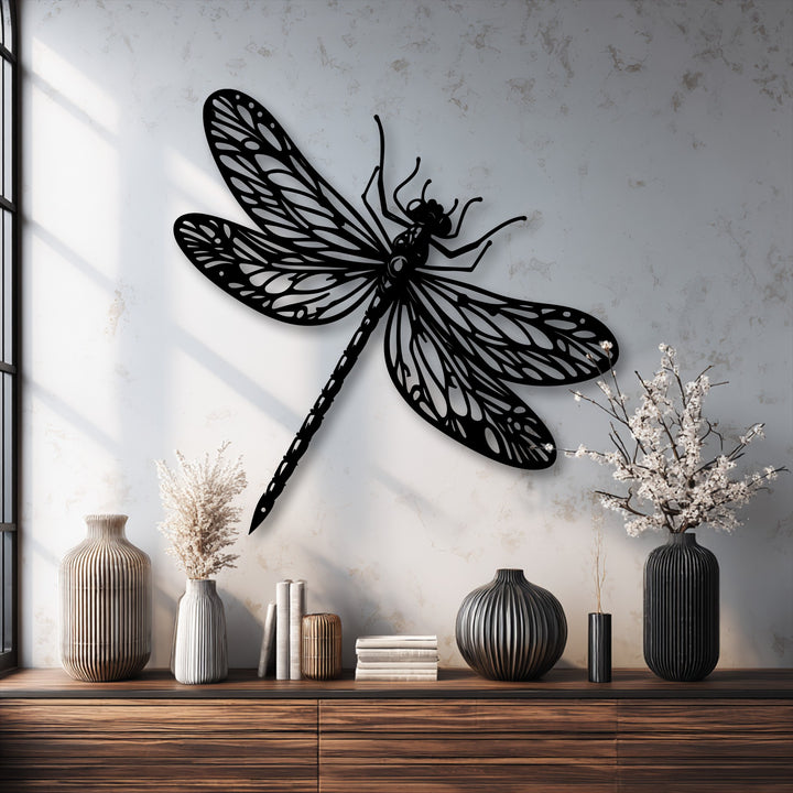Dramatic shadows from the window frame the elegant dragonfly metal art for wall, casting intricate patterns across the textured white surface.