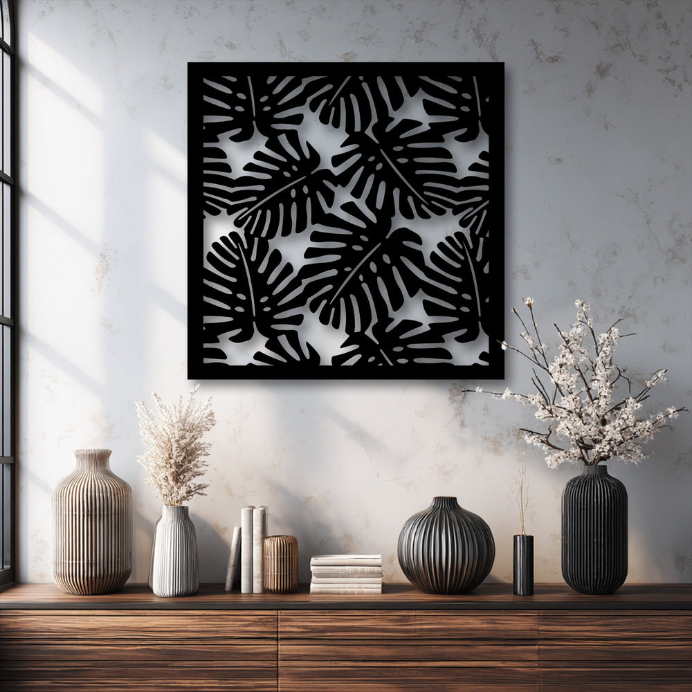 A vertically oriented rectangular piece of modern metal wall decor featuring a tropical monstera leaf pattern in black.