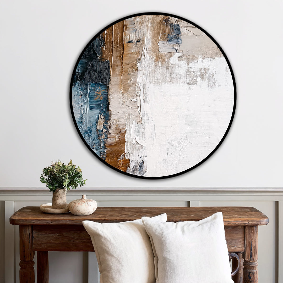 Illuminated by the brightest area, this textured abstract round oil painting art piece presents a modern, earthy horizon with strokes of cream, brown, and blue.
