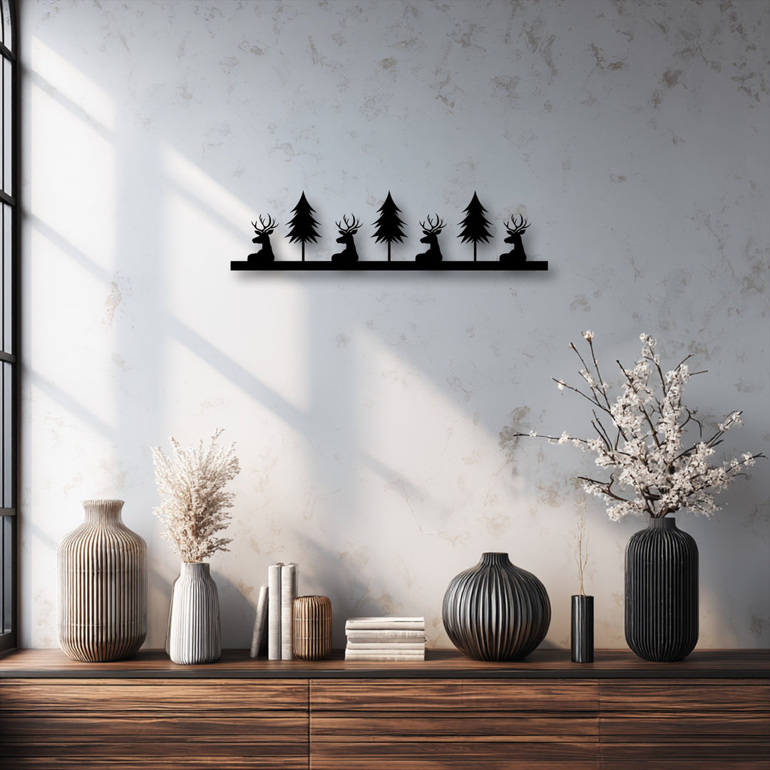 A horizontal metal artwork displaying a rectangular base with a silhouette cut-out design of deer and pine trees.