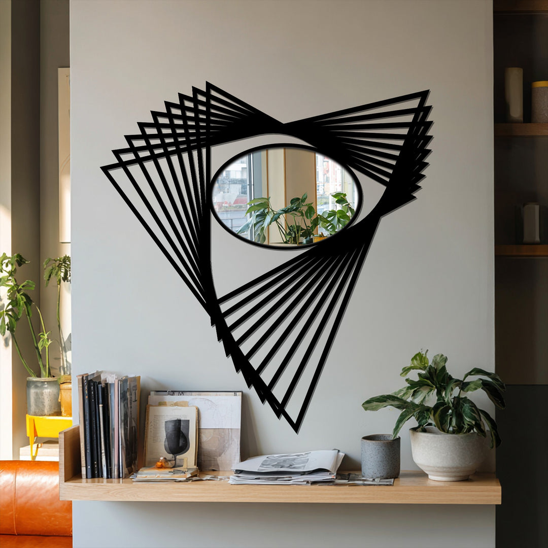 A modern framed wall mirror features an oval reflective surface surrounded by an angular, geometric metal artwork, reflecting the room and decor.