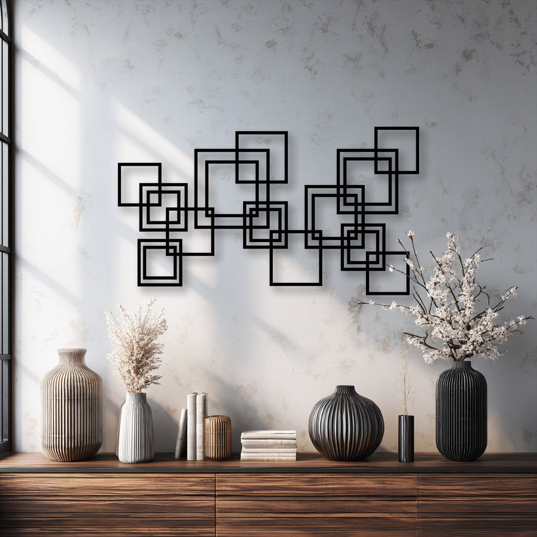 Rough, speckled wall texture contrasts with the smooth matte black finish of the unique metal wall art's modern interlocking squares.