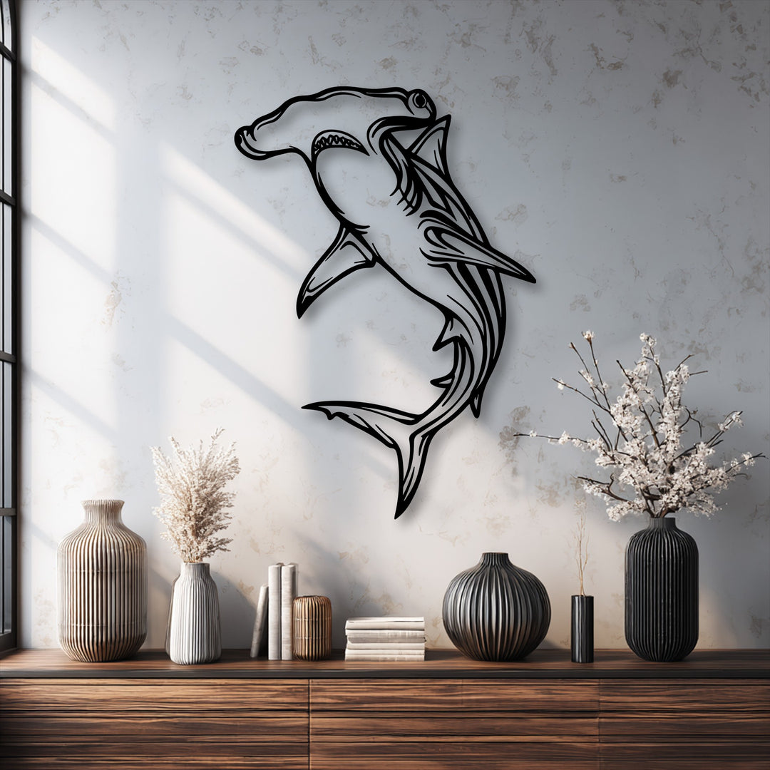The bold outline of the hammerhead shark metal wall decor creates striking negative space against the light, textured wall.