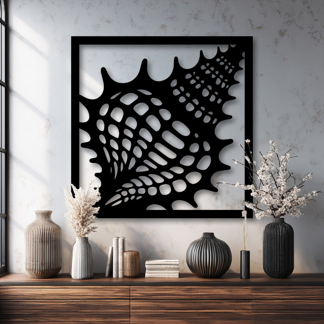 The muted color saturation of this scene beautifully emphasizes the stark black seashell frame metal wall decor against a light textured wall.