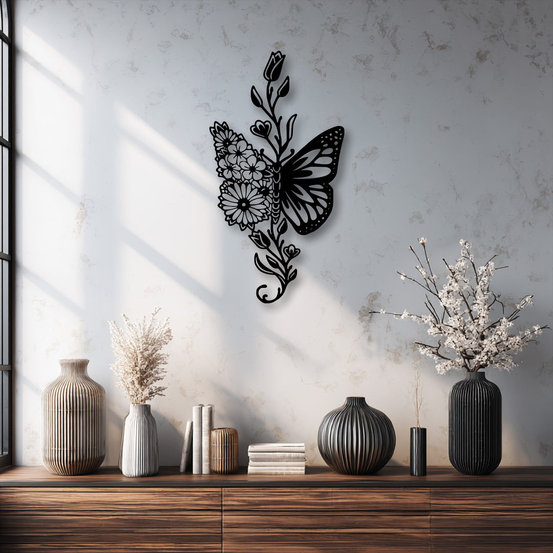 The vertical, elongated metal artwork showcases an elegant butterfly shape with one wing formed by intricate floral and botanical elements.
