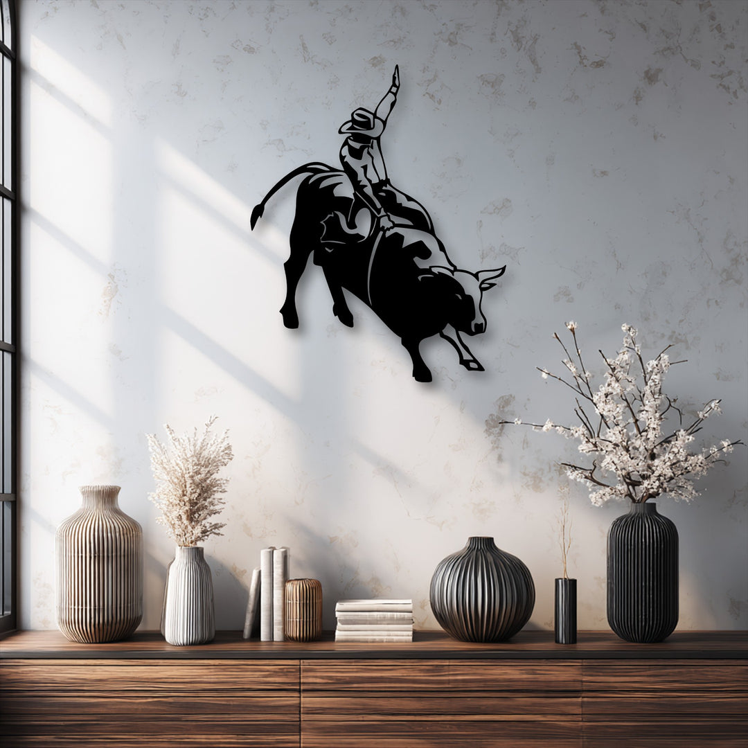 A striking black silhouette of a rodeo cowboy dynamically riding a powerful bucking bull, presented as unique metal wall art against a textured wall.