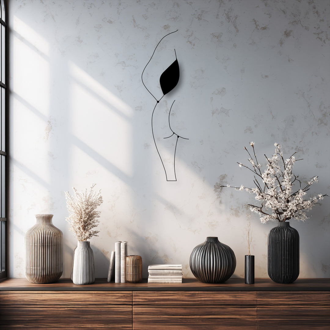 The wall's mottled surface texture contrasts with the sleek, dark lines of the minimalist female silhouette decorative metal art.