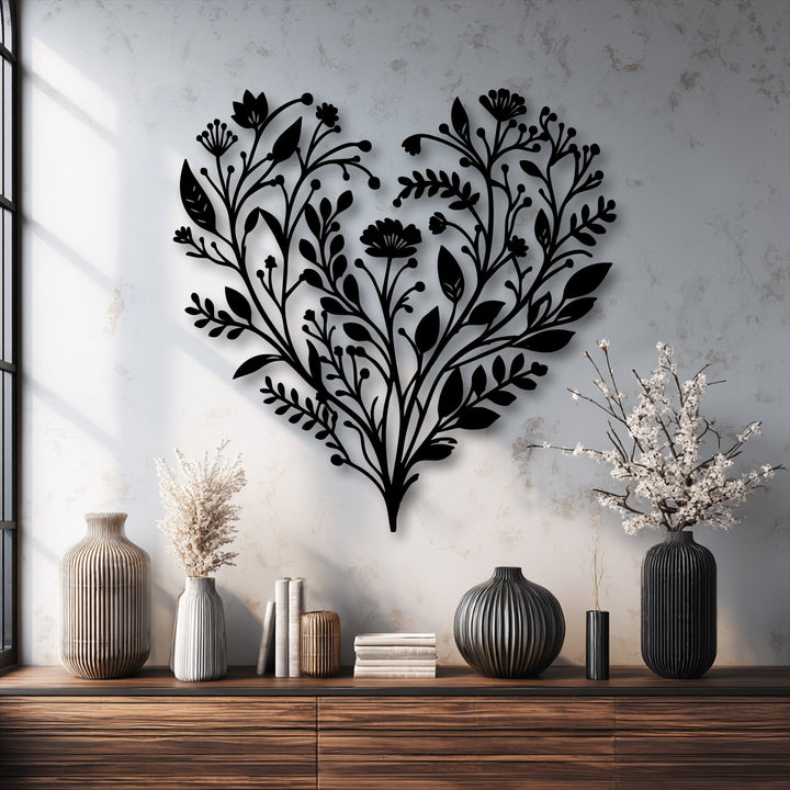 Mottled wall and grained wood frame the smooth, intricate botanical heart metal wall decor, complemented by fluted ceramic vases.