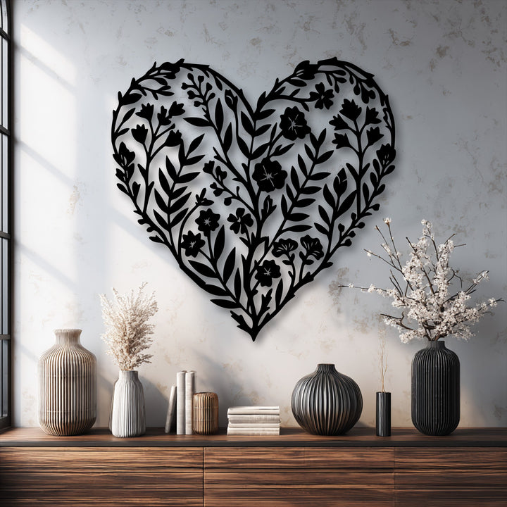The matte black unique metal wall art featuring a botanical heart silhouette contrasts beautifully against the subtly textured concrete-like wall surface.