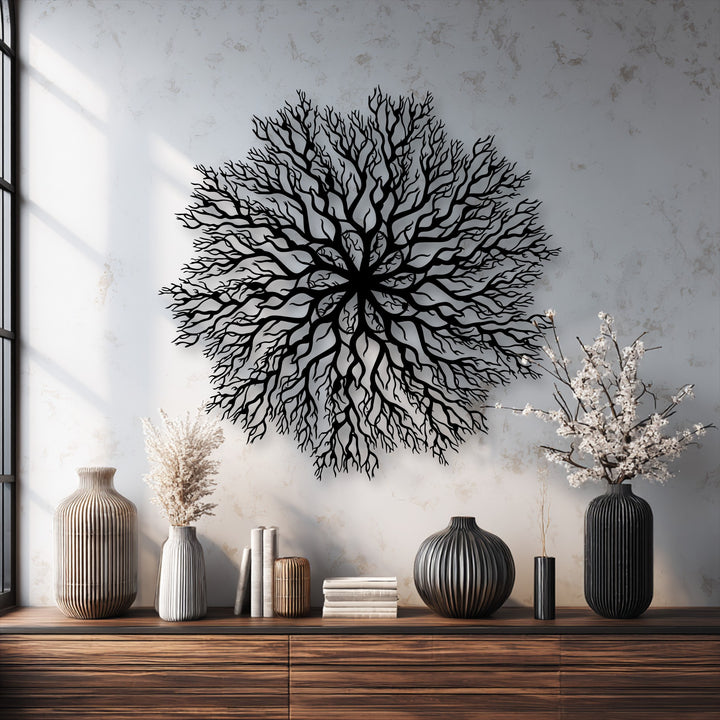 Dominant black tree roots mandala metal artwork creates a striking nature-inspired circle decor against a light, textured wall.