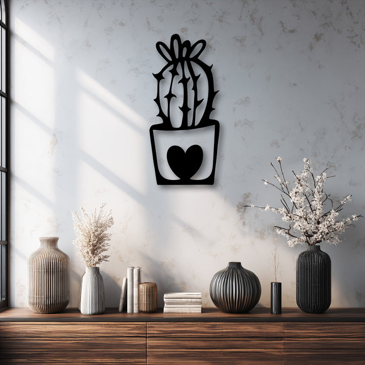 The wall's rough surface texture highlights the sleek black unique metal wall art featuring a cute cactus in a heart pot.