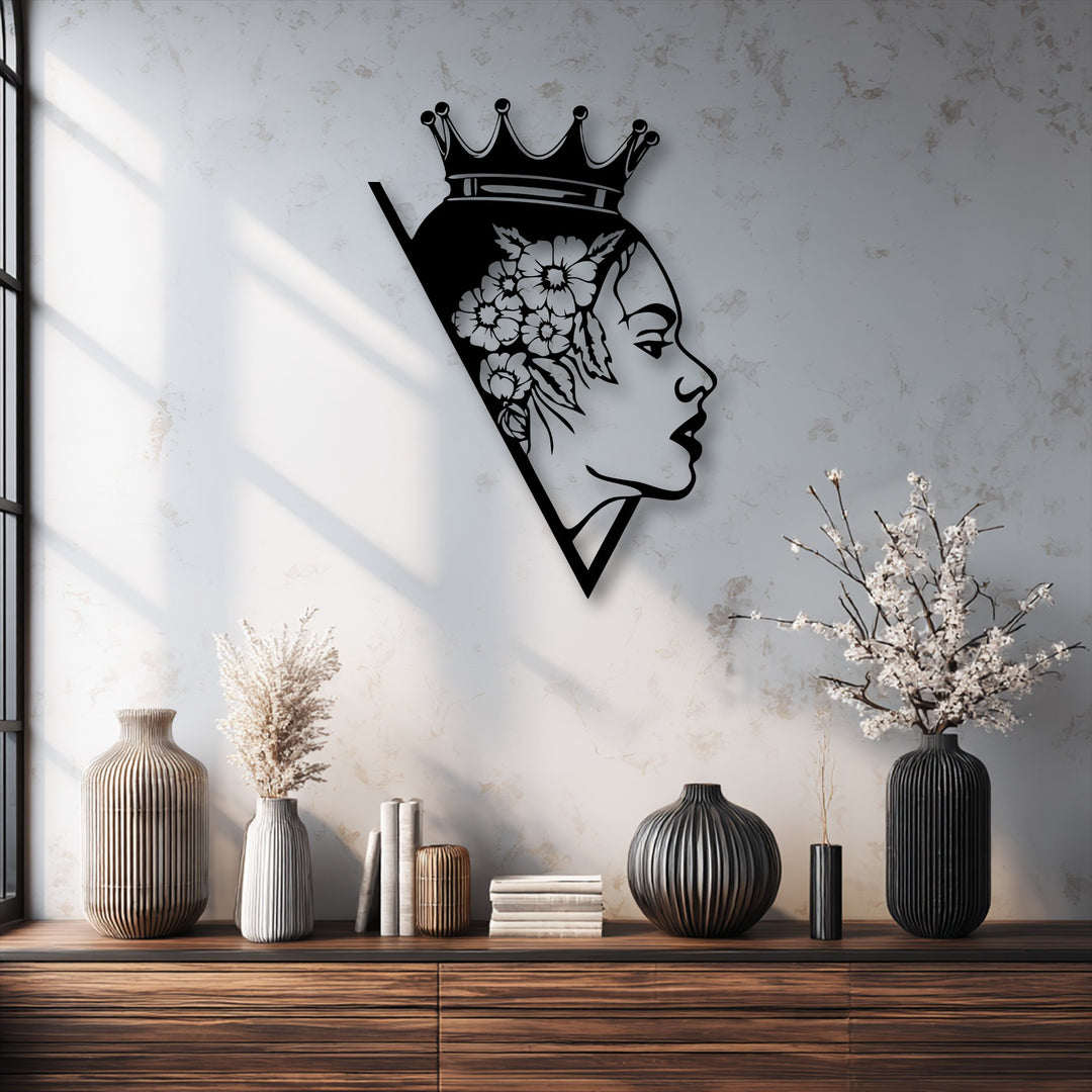 A striking black metal artwork of a woman's profile, crowned with a floral design, encased within a sharp geometric triangular silhouette.