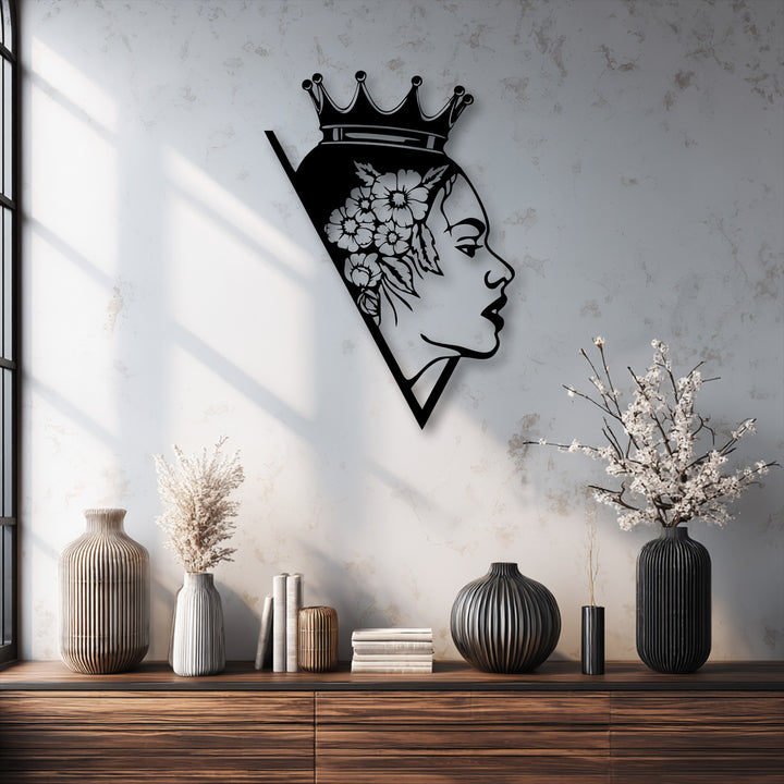 A striking black metal artwork of a woman's profile, crowned with a floral design, encased within a sharp geometric triangular silhouette.