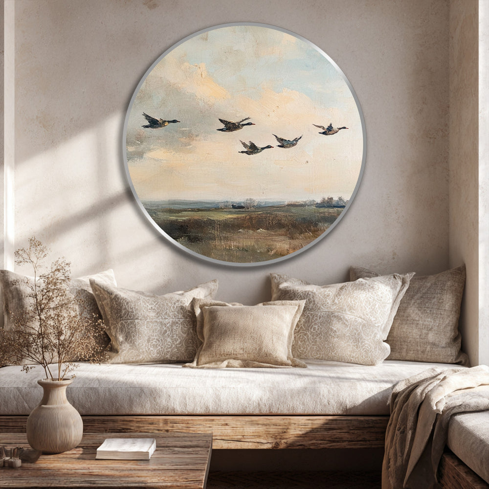 A round oil painting's silver edge softly reflects the light above a cozy nook, enhancing its vintage landscape art as stylish oil painting home decor.