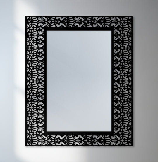 The brightest area highlights the sleek decorative mirror framed with a black metal design featuring an ornamental damask pattern.