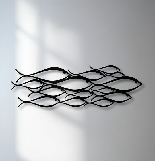 The minimalist school of fish unique metal wall art features sleek black figures that provide a stark contrast against the luminous white wall.