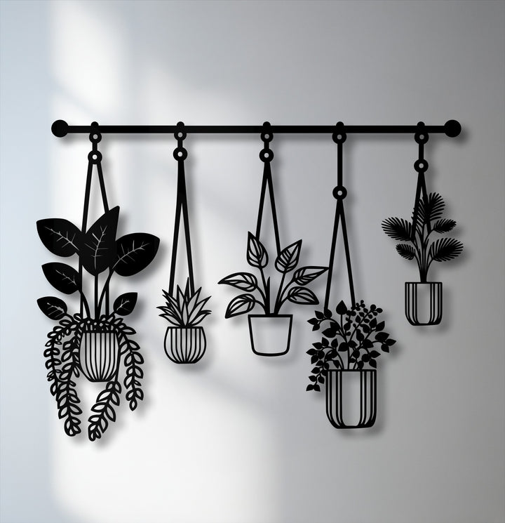 The dominant color in this decorative metal art piece is black, showcasing modern hanging plants as striking silhouettes against a light grey wall.