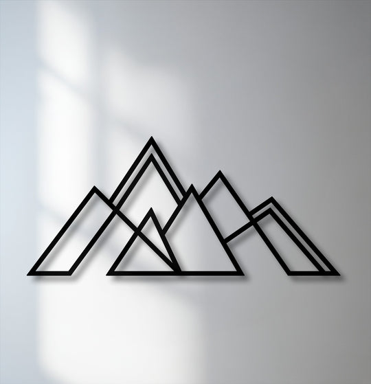 The smooth, matte finish of the geometric mountain metal wall decor contrasts with the subtle texture of the light grey wall.