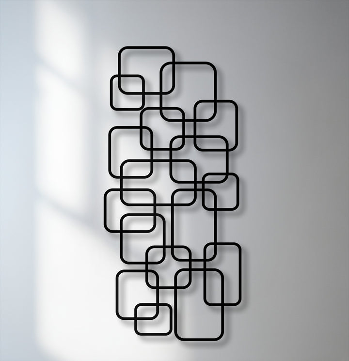 The striking color contrast of black geometric metal art for wall featuring interlocking rounded squares against a light grey background.