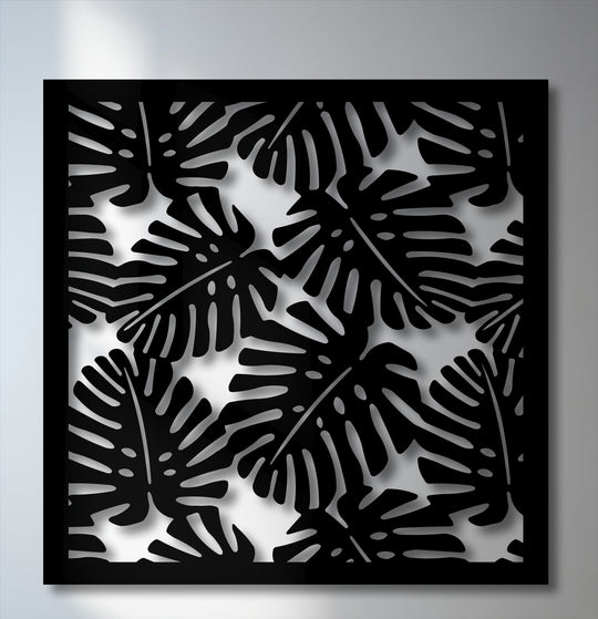 The striking black tropical Monstera leaf pattern, a compelling metal artwork, casts dramatic shadows against the light background.