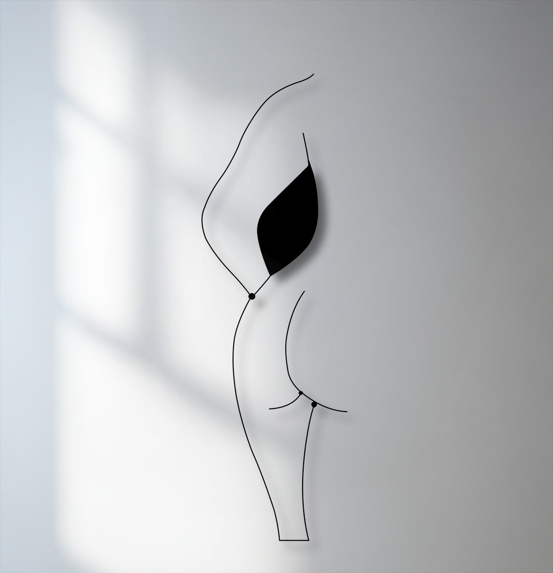 The realistic detail of the minimalist female silhouette line art is highlighted by its sleek black unique metal wall art form and subtle wall shadows.