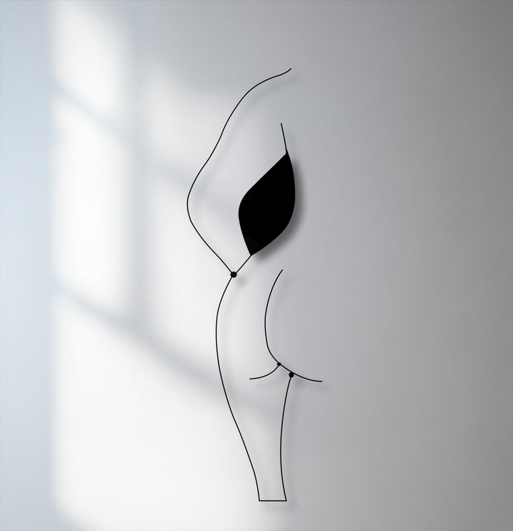 The realistic detail of the minimalist female silhouette line art is highlighted by its sleek black unique metal wall art form and subtle wall shadows.