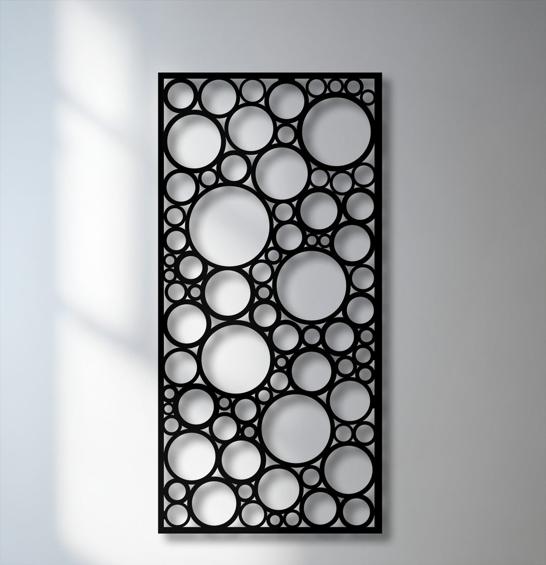 Dramatic light and shadow define the varied circular cutouts of this abstract geometric metal wall decor, creating depth.