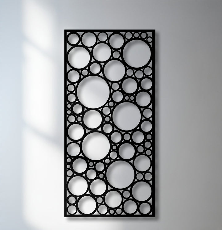 Dramatic light and shadow define the varied circular cutouts of this abstract geometric metal wall decor, creating depth.