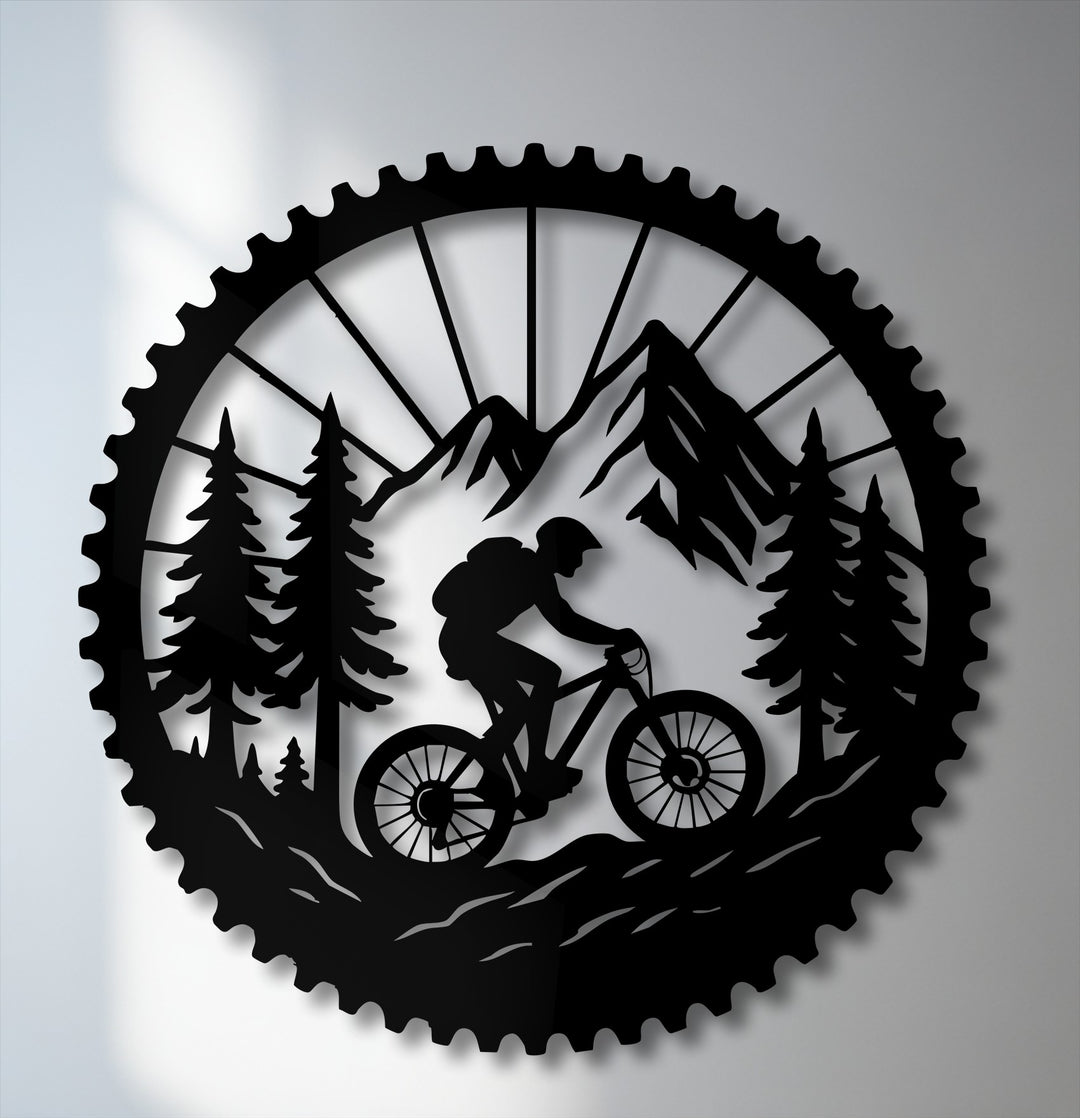 A bold, high-contrast decorative metal art piece featuring a black silhouette of a mountain biker in a forest within a gear shape on a light background.