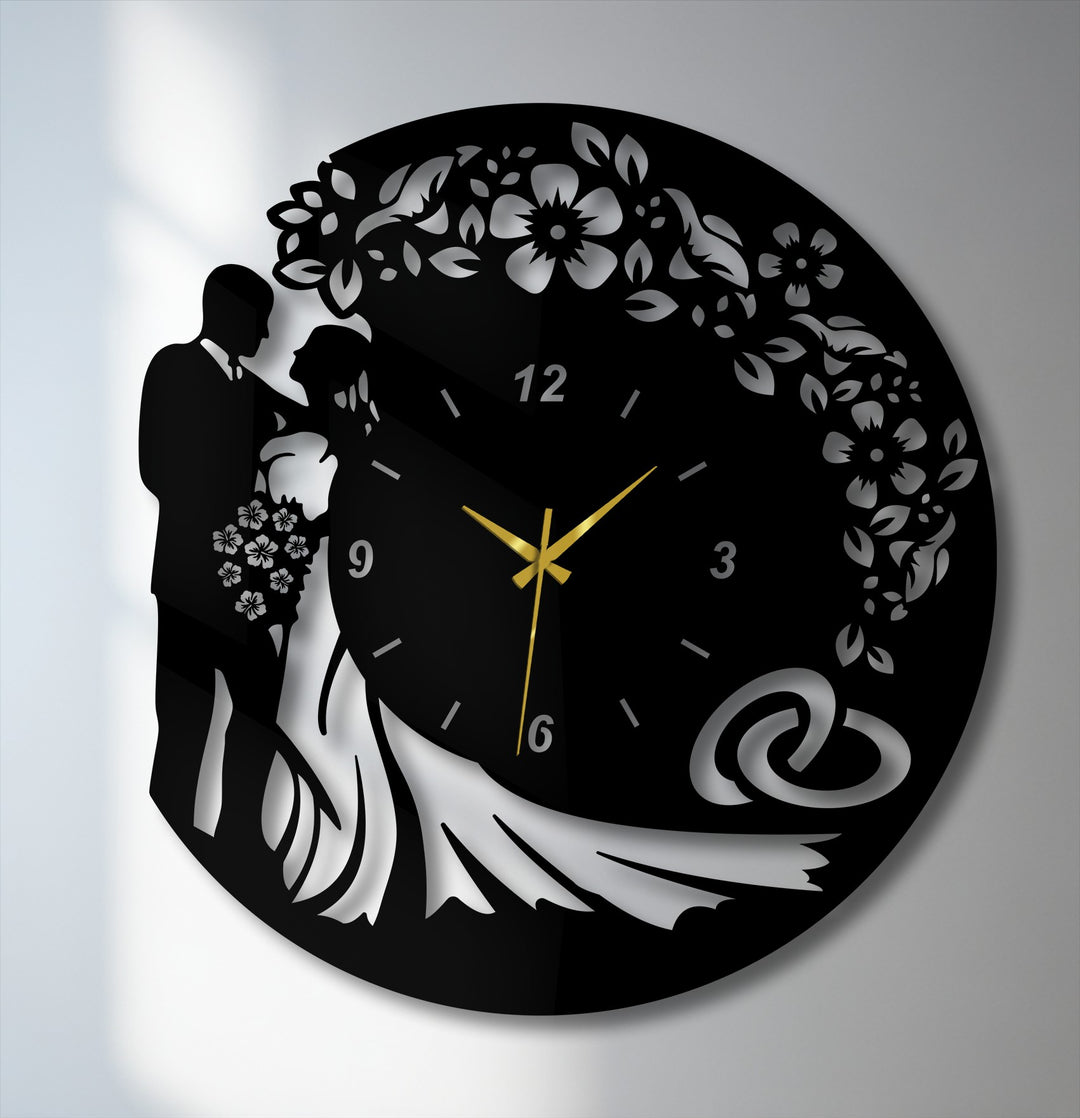 Surface texture highlights the decorative metal art wall clock's matte black metal contrasting with glossy, reflective wedding silhouettes and details.