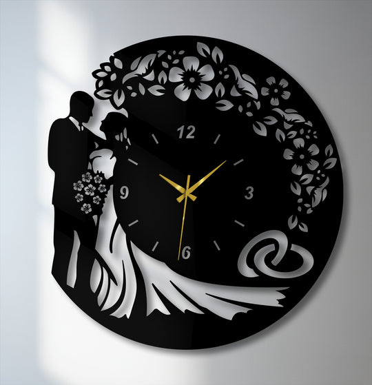 Surface texture highlights the decorative metal art wall clock's matte black metal contrasting with glossy, reflective wedding silhouettes and details.