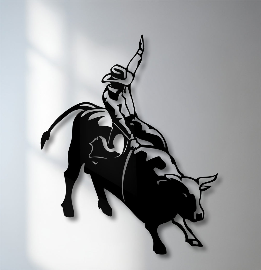 The smooth, matte surface texture of the black metal wall decor depicts a dynamic rodeo cowboy on a bucking bull silhouette.