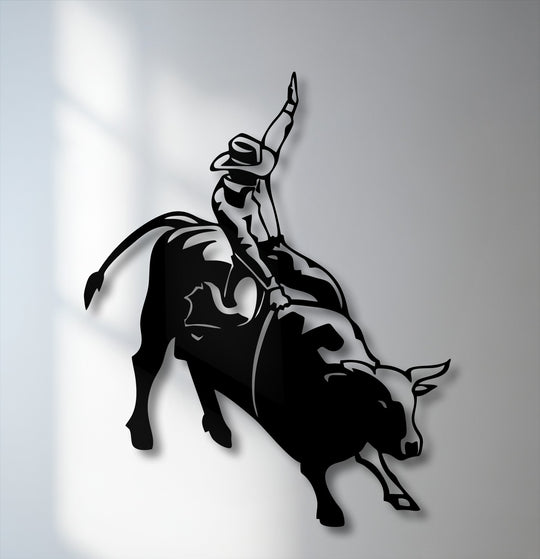 The smooth, matte surface texture of the black metal wall decor depicts a dynamic rodeo cowboy on a bucking bull silhouette.