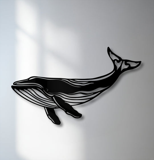The subtle, diffused white and light gray wall background highlights the majestic whale silhouette metal wall decor.