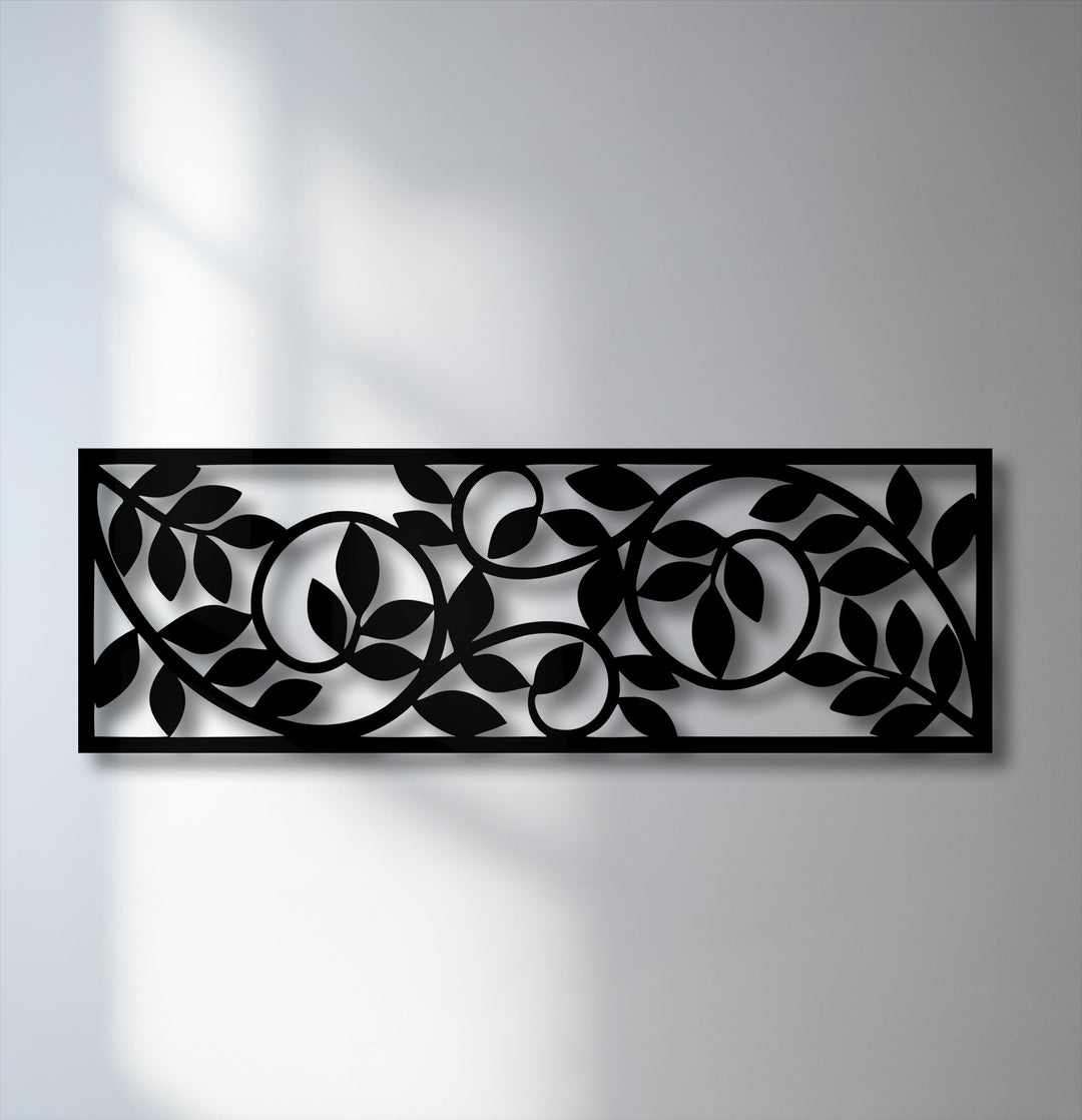 The intricate black metal artwork panel features a flowing botanical vine pattern with stylized leaves, casting elegant shadows on the wall.
