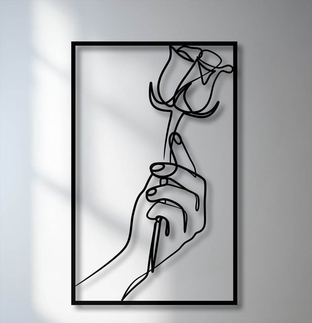 The sleek matte finish of this minimalist hand holding rose metal wall decor highlights the elegant line art design.
