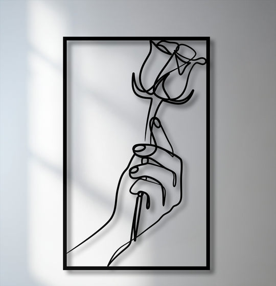 The sleek matte finish of this minimalist hand holding rose metal wall decor highlights the elegant line art design.