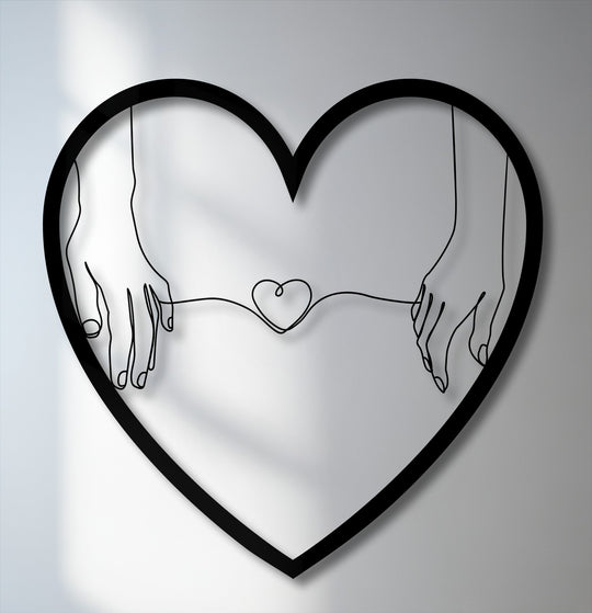 Striking decorative metal art in the foreground shows minimalist hands holding a line that forms a small heart, framed by a larger heart.