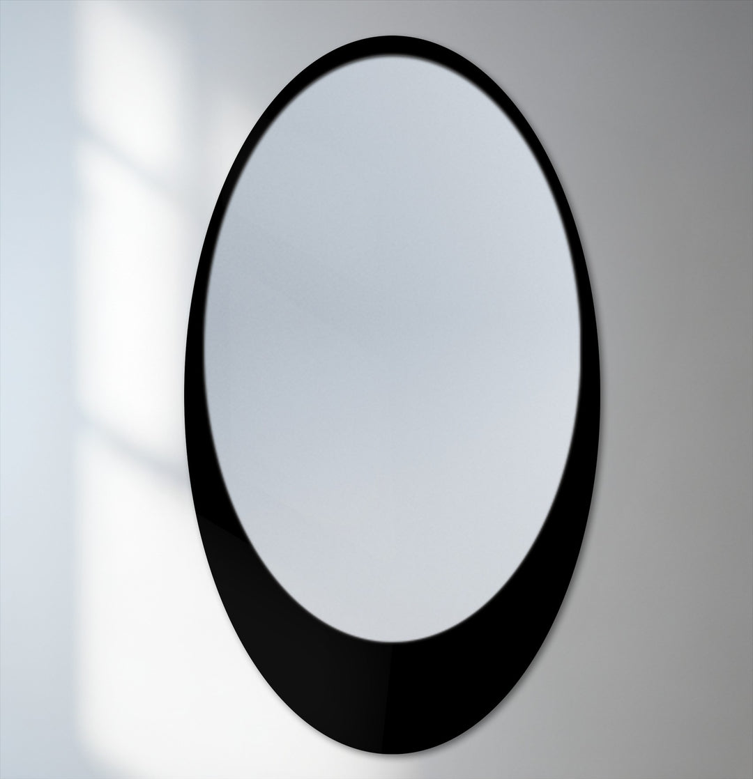 Light and shadow emphasize the sleek curve and reflective surface of this minimal oval floor decorative mirror with a black frame.
