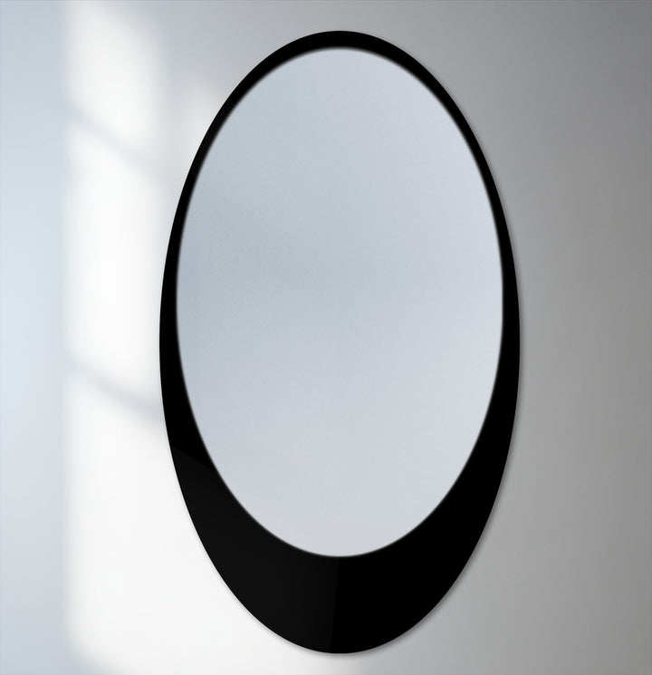 Light and shadow emphasize the sleek curve and reflective surface of this minimal oval floor decorative mirror with a black frame.