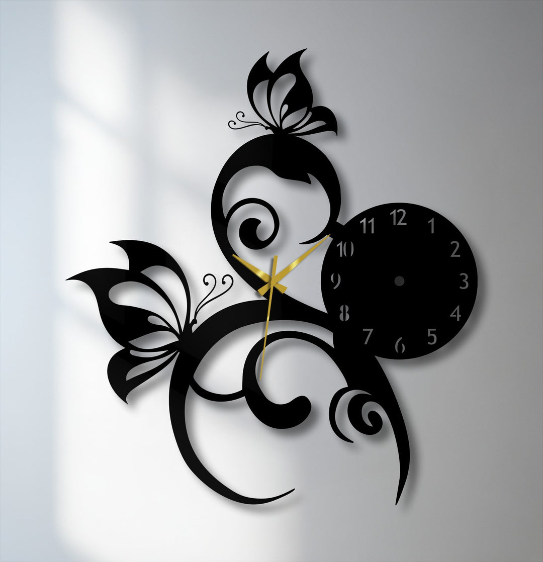 The striking negative space formed by the black butterfly vine metal wall clock's elegant design showcases the decorative metal art against a light background.