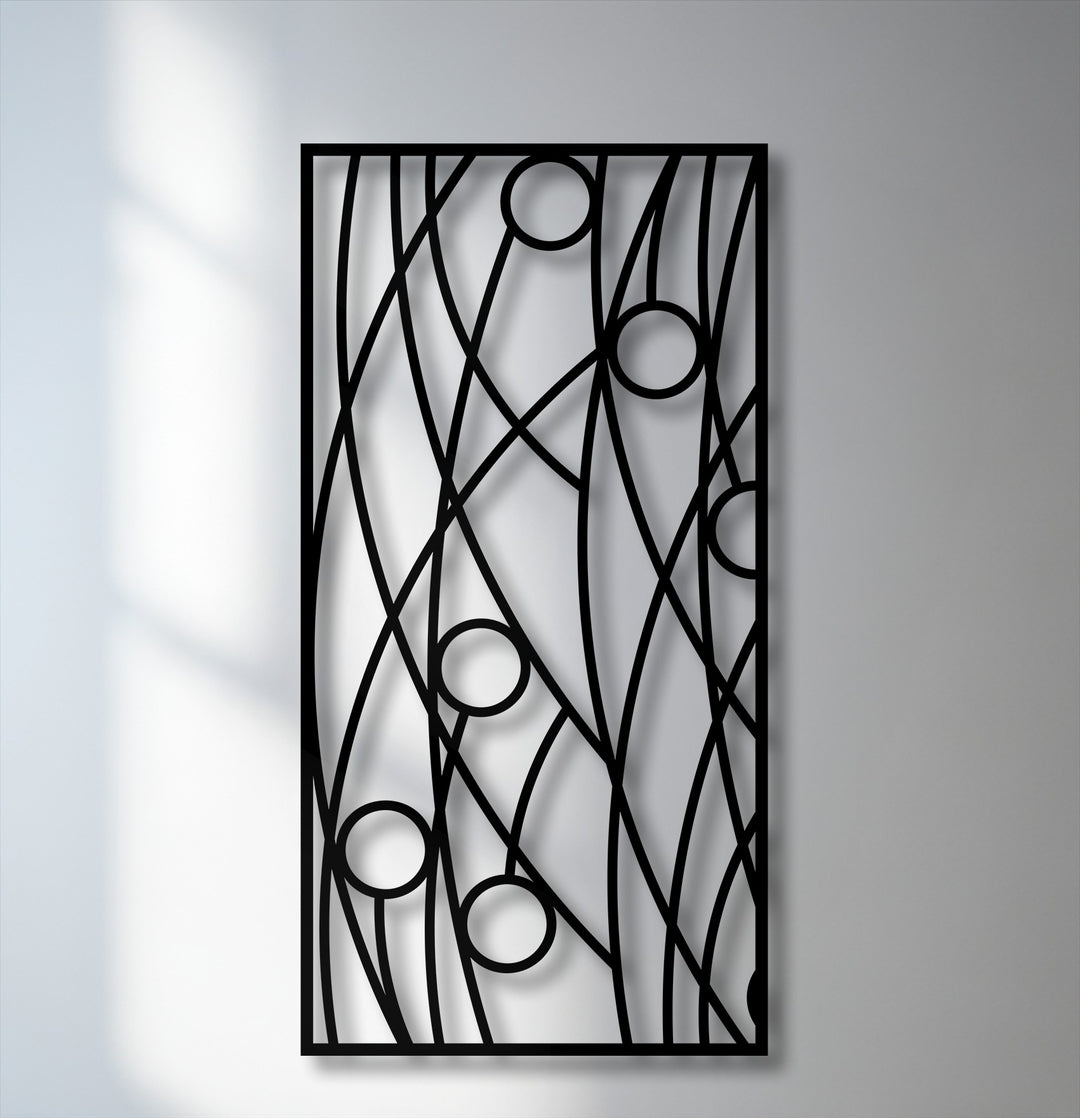 The background reveals a simple light grey wall and a brighter white wall with soft shadows, enhancing the unique metal wall art panel design.