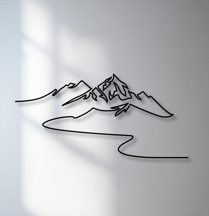The brightest area illuminates the modern minimalist mountain metal art for wall, casting sharp shadows on the light gray wall surface.
