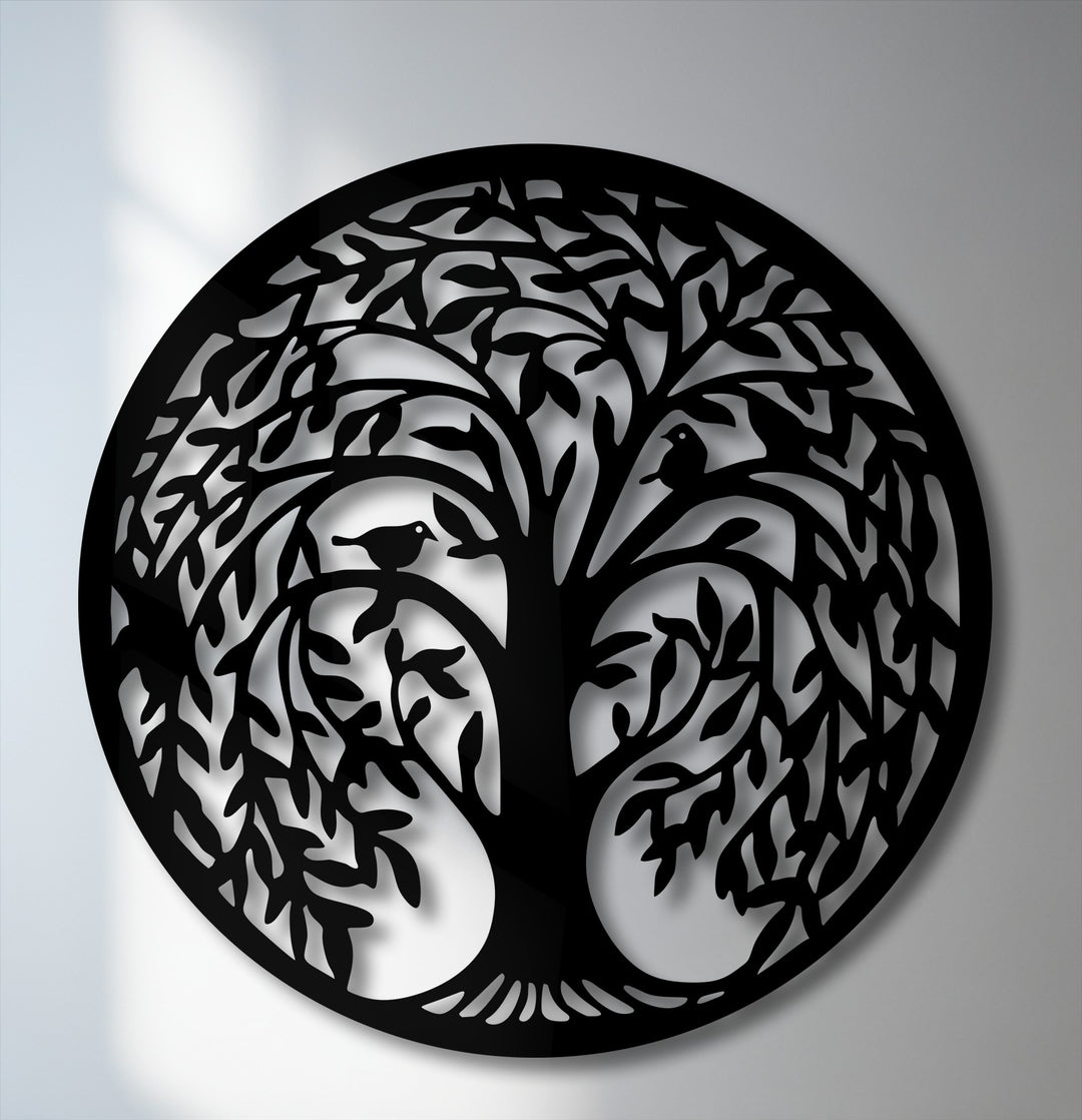 The cool color temperature highlights the intricate black Tree of Life circular silhouette, a unique metal wall art piece with birds perched in its branches.