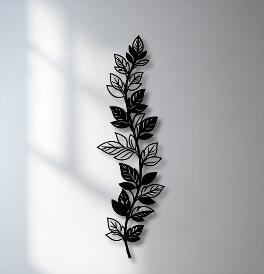 The brightest area of the white wall, illuminated by soft window light and subtle shadows, highlights the elegant botanical leaf metal artwork.