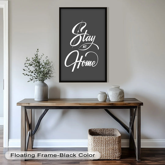Foreground details highlight a rustic wood console table beneath this modern oil painting art, displaying a monochromatic typographic 'Stay at Home' design.