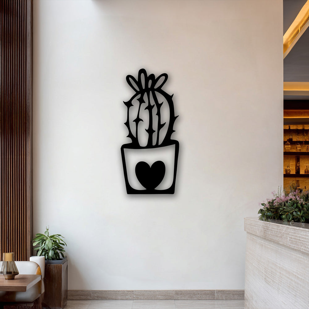 A dramatic transition of color is evident between the black cute cactus metal wall decor with its heart pot and the subtly illuminated cream-toned background.