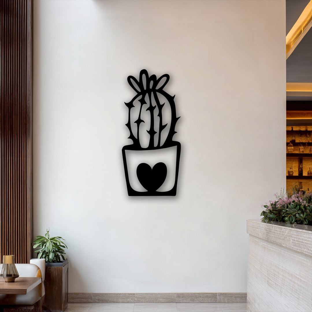 A dramatic transition of color is evident between the black cute cactus metal wall decor with its heart pot and the subtly illuminated cream-toned background.